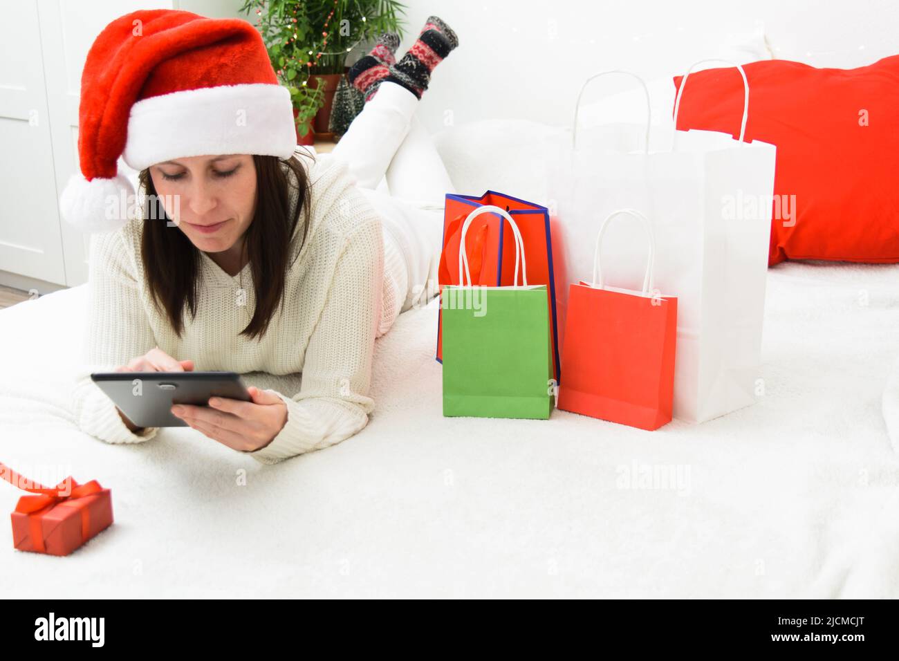 Schöne lächelnde Frau in Santa Hut hält Telefon und Bank Plastikkarte Stockfoto