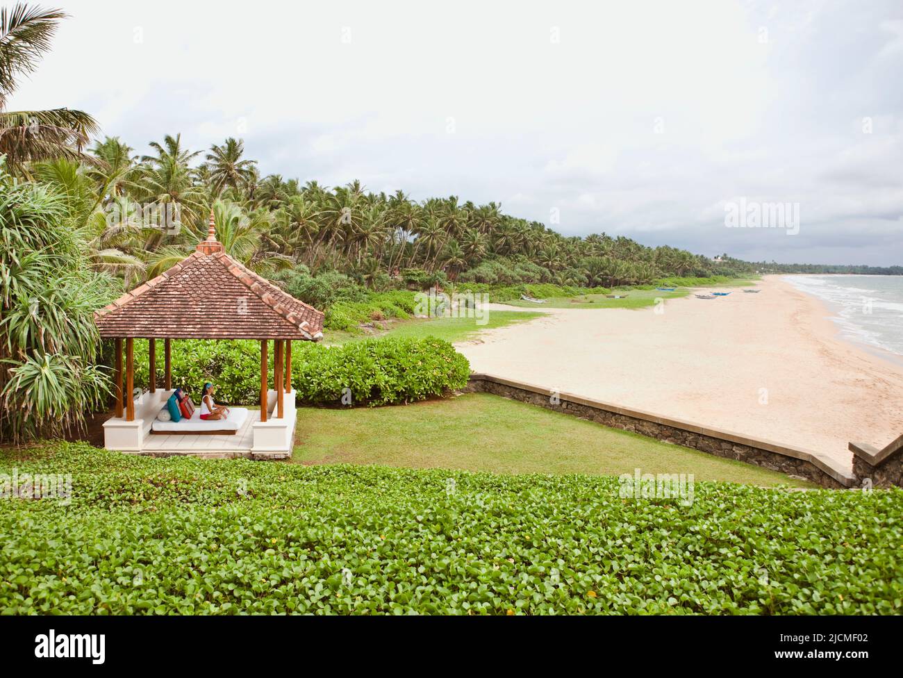 Eine Frau entspannt sich auf einem Tagesbett in einer Cabana am Meer. Aturuwella, Bentota, Sri Lanka. Stockfoto