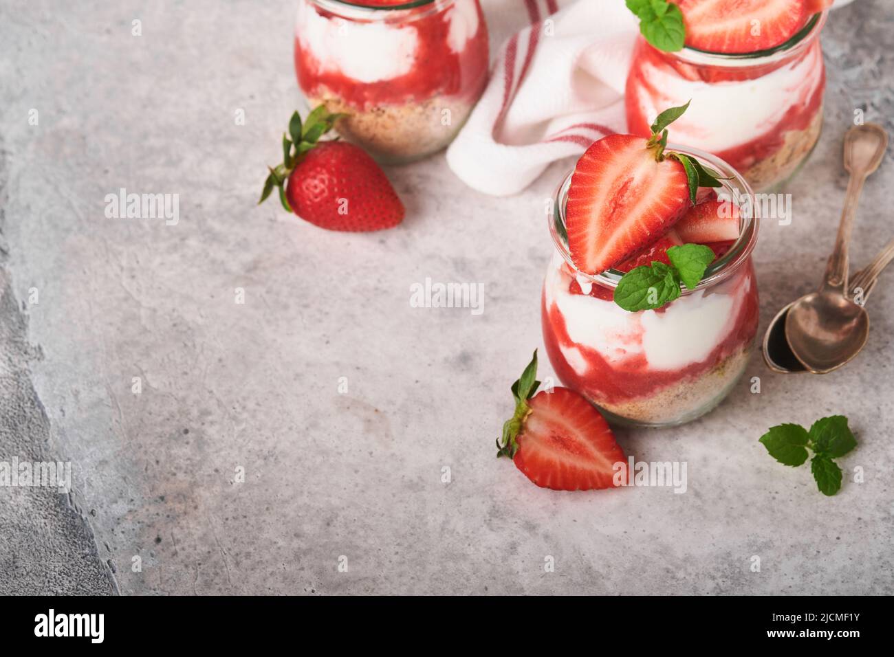 Erdbeerkäsekuchen. Käsekuchen oder Kleinigkeit mit Erdbeere im Glas auf altem grauen Beton Hintergrund Tischhintergrund. Käsekuchen ohne Backen. Abs Stockfoto