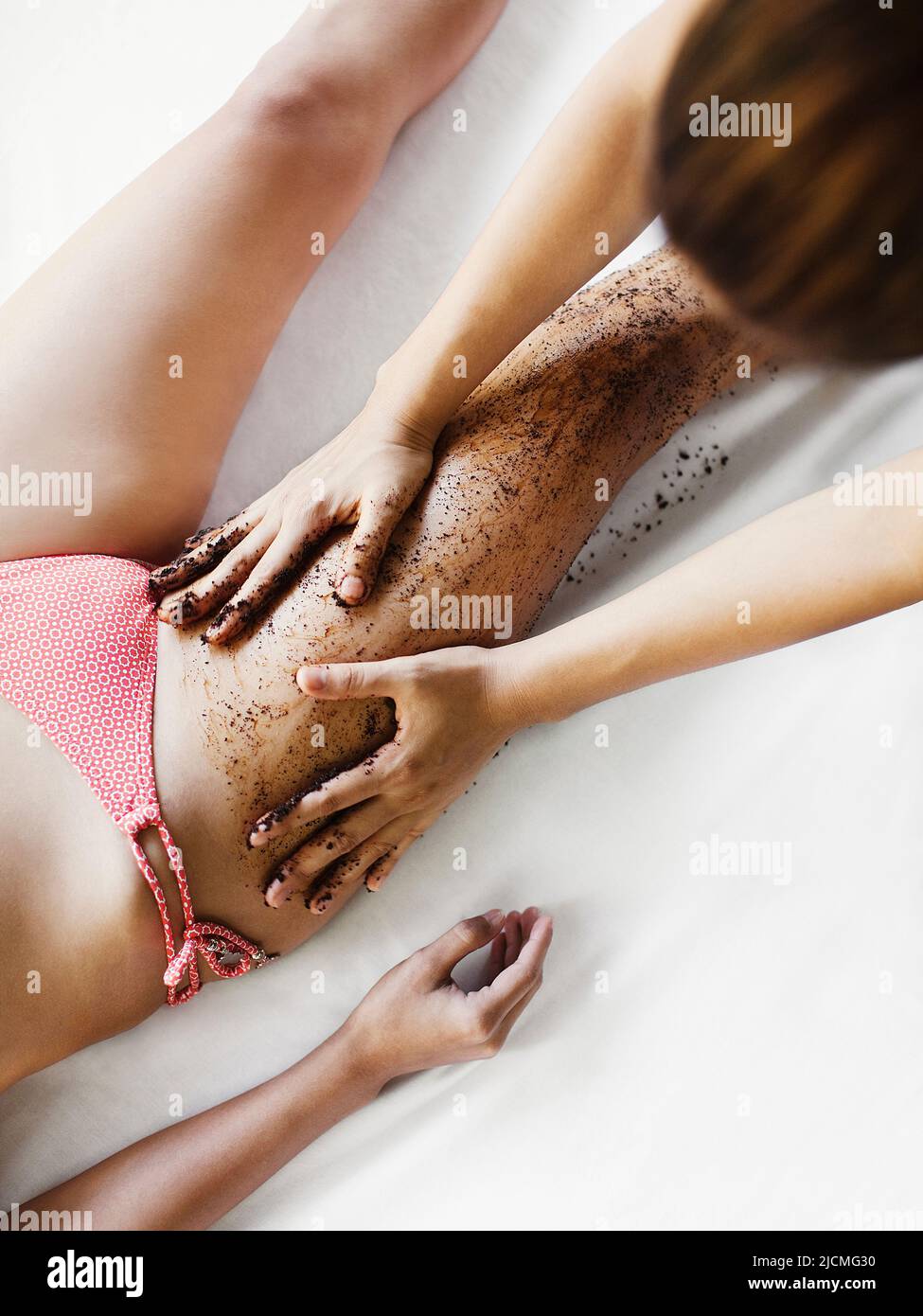 Frau Erhält Kaffeeschrubben. Thailand. Eine Frau erhält ein Kaffee-Körperpeeling im Freien in einer Cabana am Pool. Stockfoto