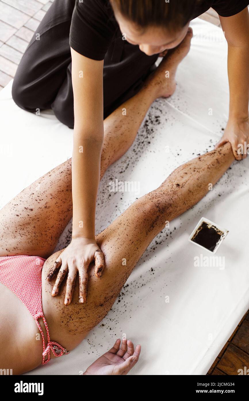 Frau Erhält Kaffeeschrubben. Thailand. Eine Frau erhält ein Kaffee-Körperpeeling im Freien in einer Cabana am Pool. Stockfoto