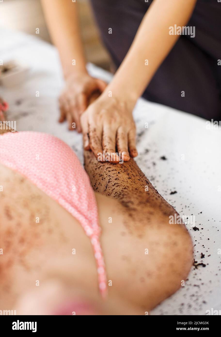 Frau Erhält Kaffeeschrubben. Thailand. Eine Frau erhält ein Kaffee-Körperpeeling im Freien in einer Cabana am Pool. Stockfoto