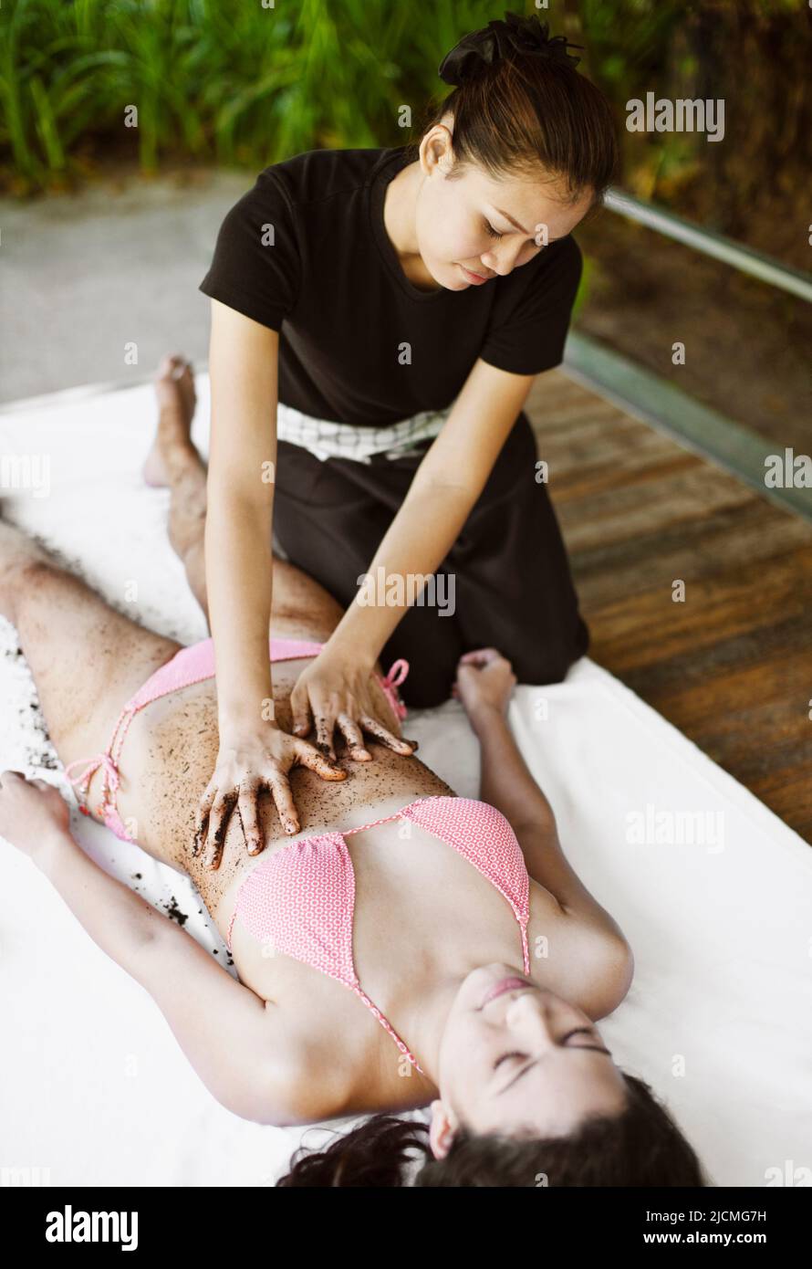 Frau Erhält Kaffeeschrubben. Thailand. Eine Frau erhält ein Kaffee-Körperpeeling im Freien in einer Cabana am Pool. Stockfoto
