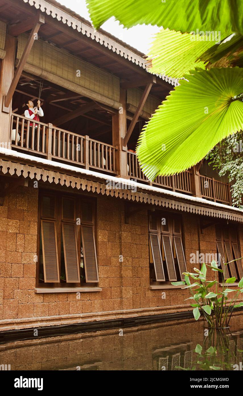 Ein Hotelmitarbeiter zieht die Jalousien der Lounge im zweiten Stock an, um das Morgenlicht in einem Hotel, Siem Reap, Kambodscha, einzulassen. Stockfoto