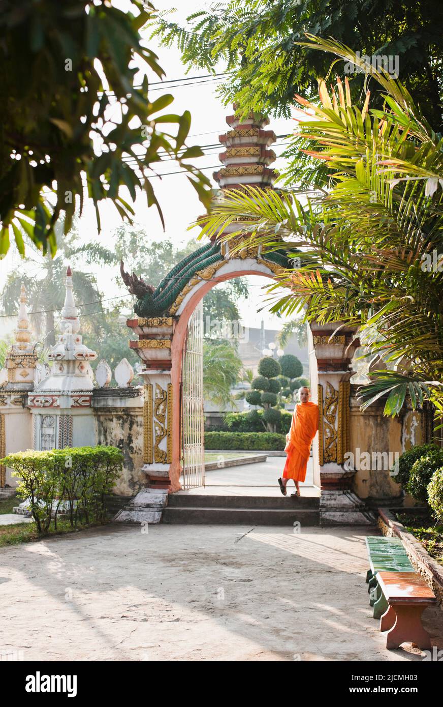 Ein junger Mönch entspannt sich an einer Tür im Wat Si Muang, Vientiane, Laos, P.D.R. Wat Si Muang ist ein buddhistischer Tempel, der für Glück und Glück berühmt ist. Stockfoto