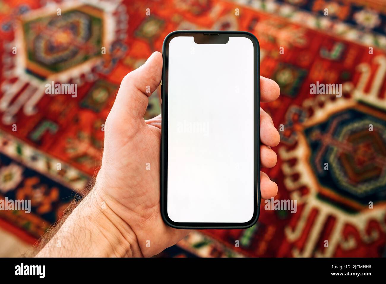 Smartphone-Mockup, Internet der Dinge und Smart-Home-Konzept, Mann mit Mobiltelefon. Nahaufnahme der Handhaltevorrichtung mit leerem Bildschirm im Home Interi Stockfoto
