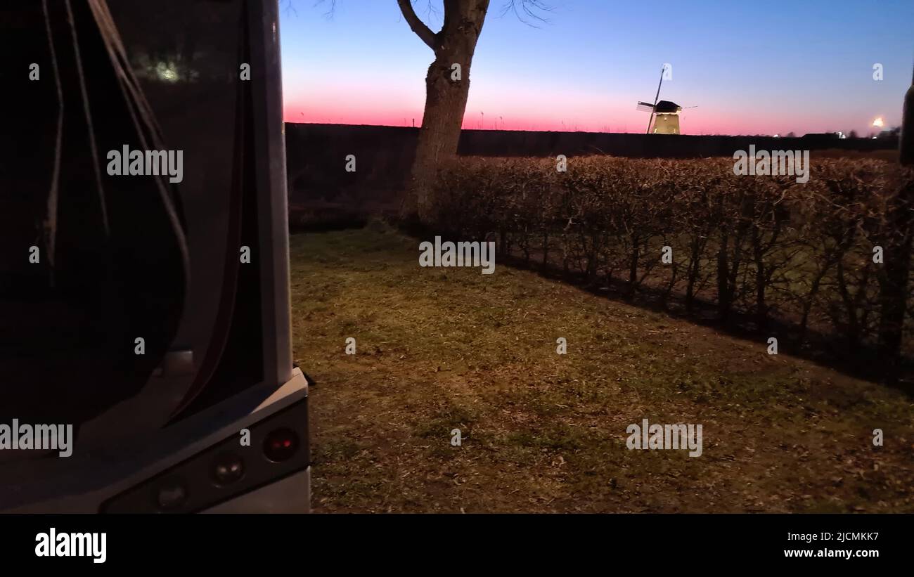 Wohnmobil im Sonnenuntergang im Hintergrund eine holländische Windmühle Stockfoto