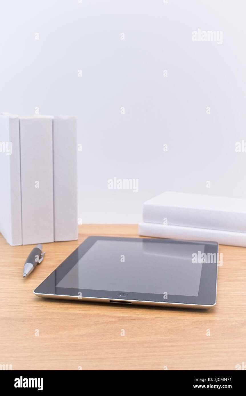 Apple ipad Tablet mit Bücher Stylus Stift auf einem hellen Holzschreibtisch an der weißen Wand Stockfoto