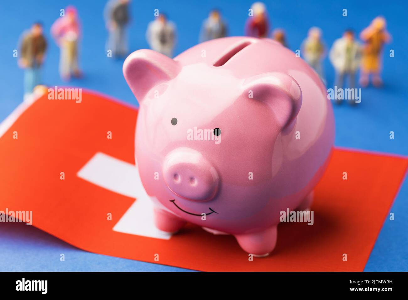 Sparschwein, Fahne und Plastikspielzeug auf farbigem Hintergrund, Einkommenskonzept in der Schweiz Stockfoto