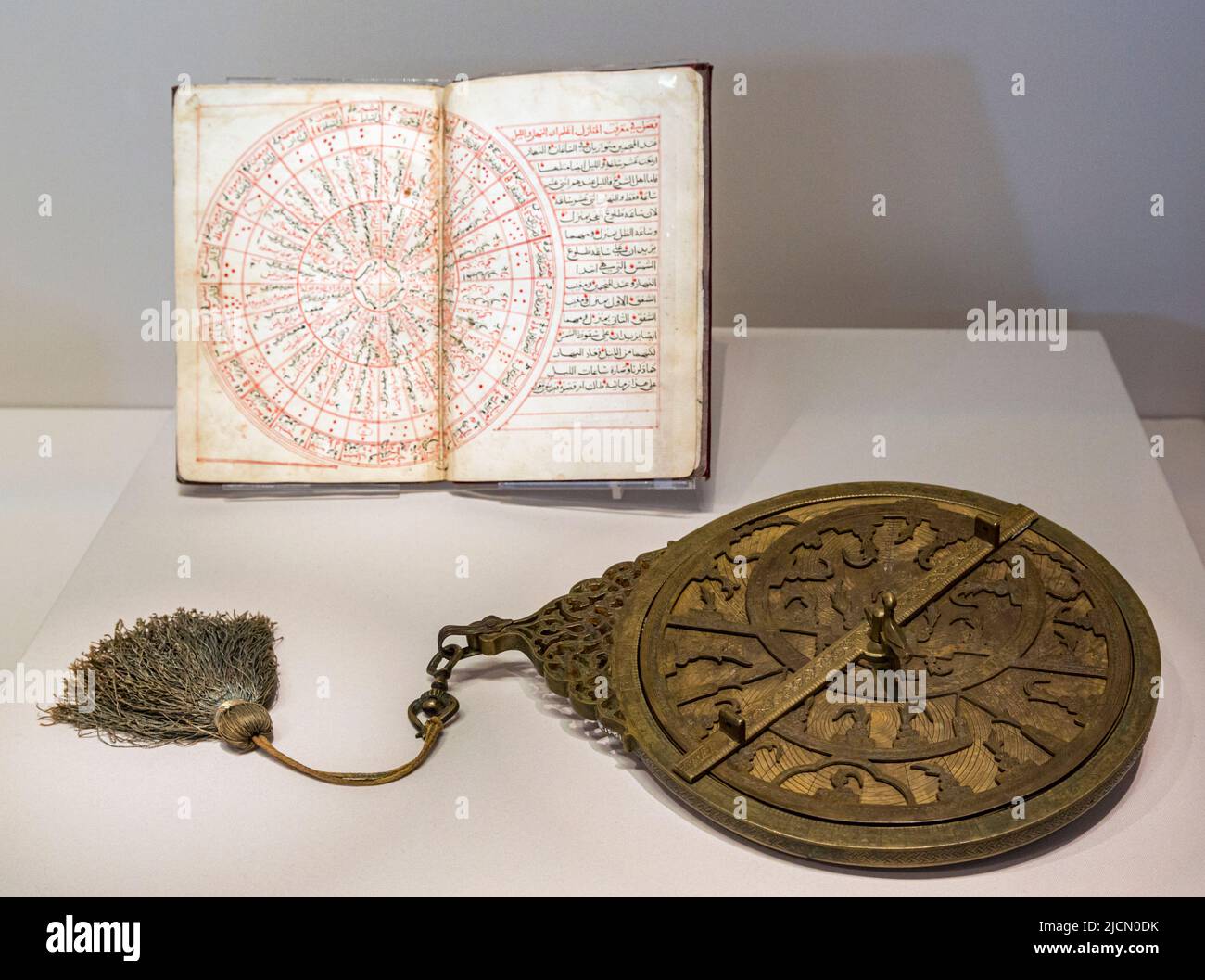 Iranisches planispher Astrolabium aus dem 19.. Jahrhundert. Im Hintergrund eine astronomische Abhandlung aus dem Jahr 1504 aus Kairo, Ägypten. Das Buch wurde verfasst Stockfoto