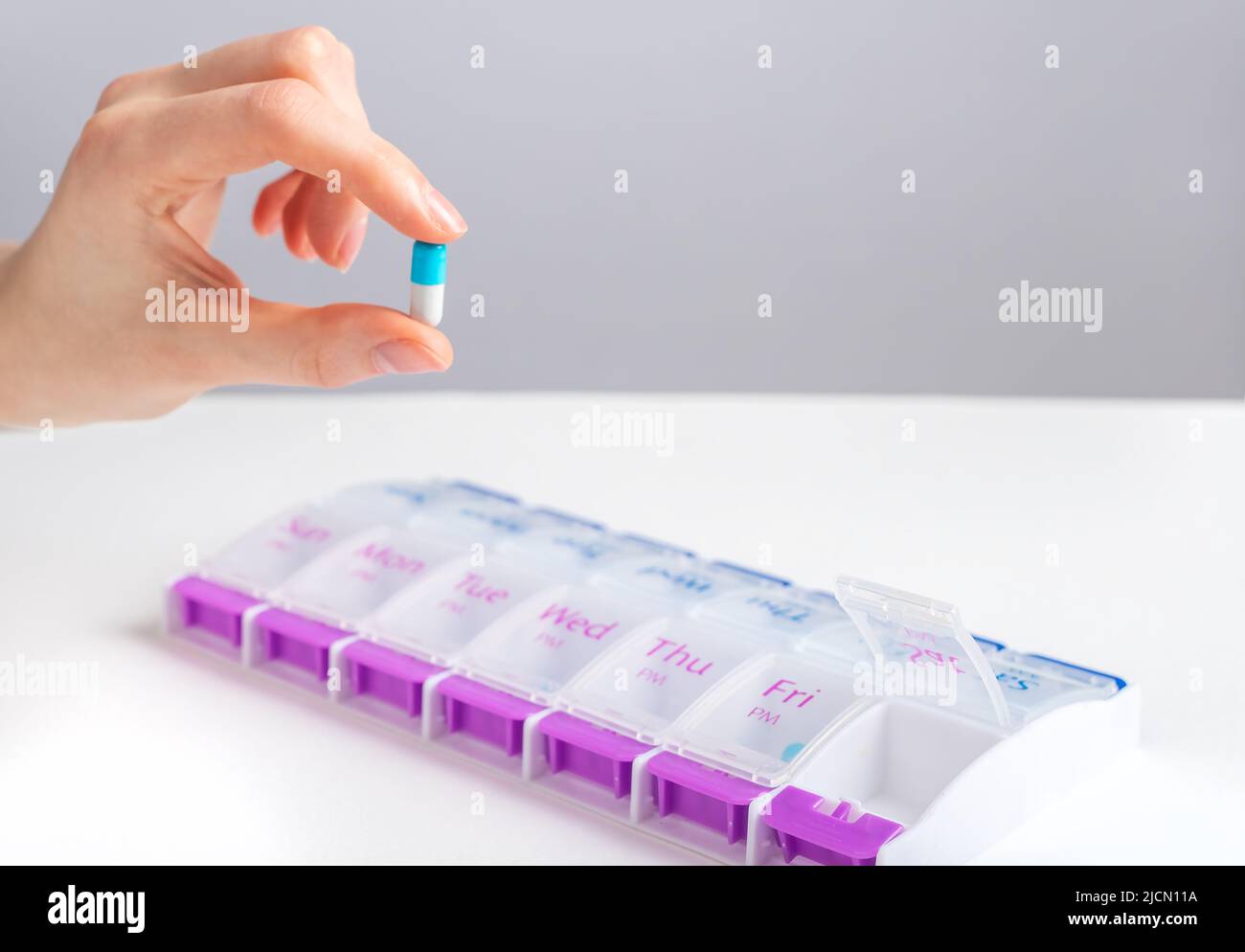 Hand, die die Kapsel in der Nähe der Tablette hält, Schachtel. Hochwertige Fotos Stockfoto