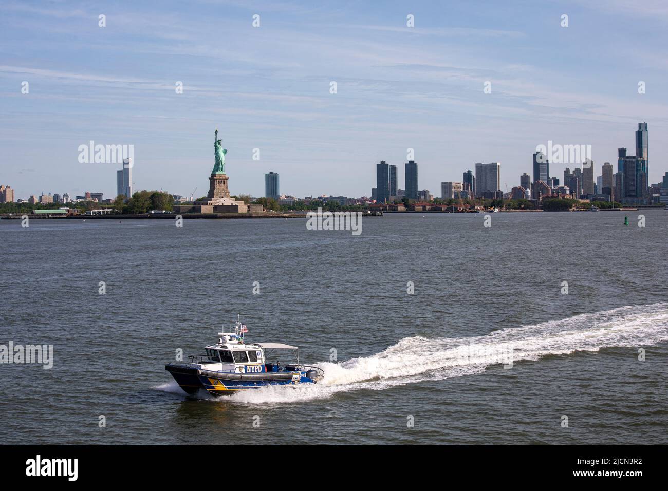 Polizeiboot der NYPD Harbour Unit mit Freiheitsstatue im Hintergrund in New York City, Vereinigte Staaten von Amerika Stockfoto