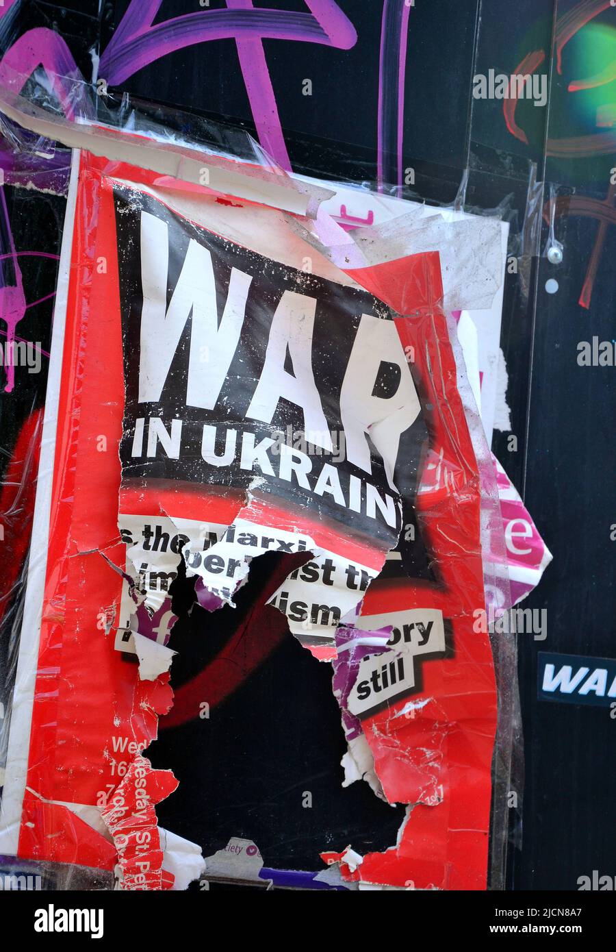 Ein beschädigtes oder vandalisiertes „war in Ukraine“-Poster an einer Wand mit Graffiti darauf in Manchester, England, Großbritannien und den Britischen Inseln Stockfoto