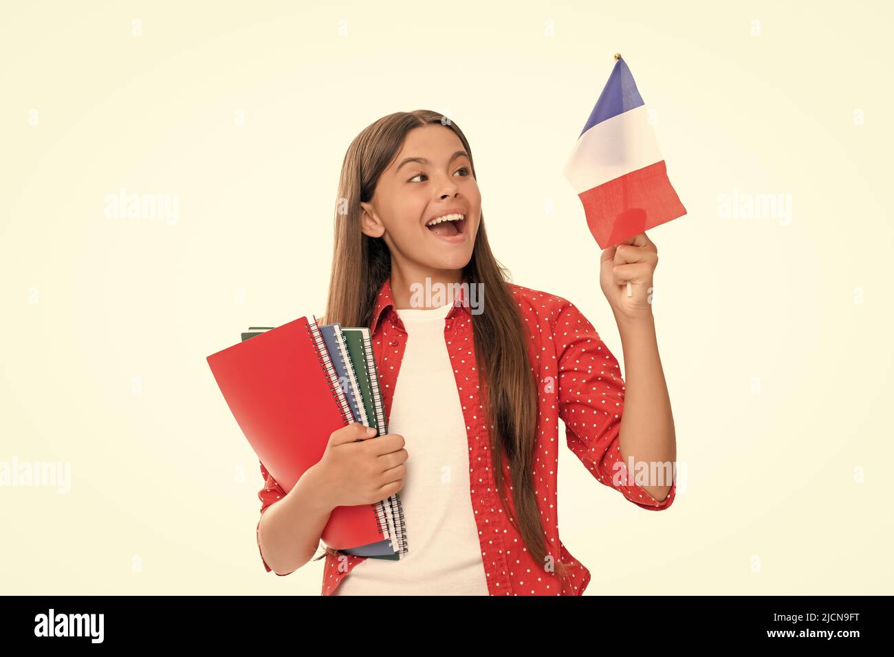 Reise nach frankreich. Lerne Fremdsprache. Überrascht jugendliches Mädchen halten französische Flagge und Arbeitsbuch. schengen-Länder. Touristenvisum. Zurück zur Schule. educa Stockfoto