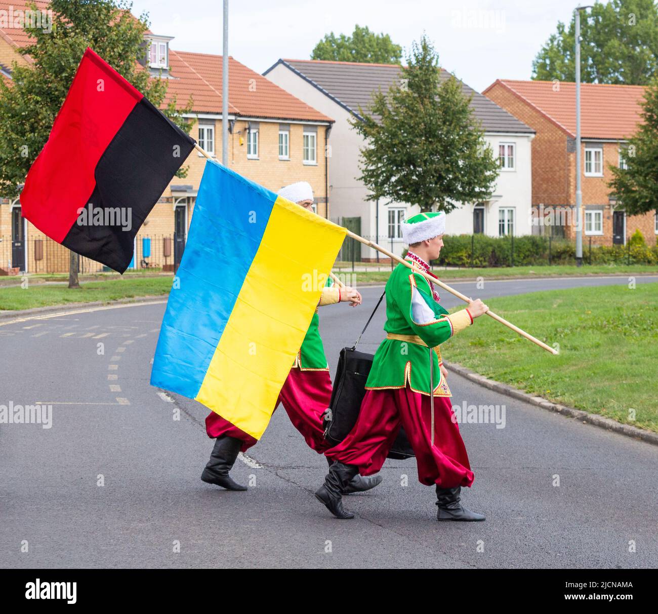 Männer aus der ukrainischen Tanzgruppe in traditioneller Kleidung. Eine Flagge der Ukraine und eine Flagge der ukrainischen Aufständischen Armee (schwarz und rot). Stockfoto
