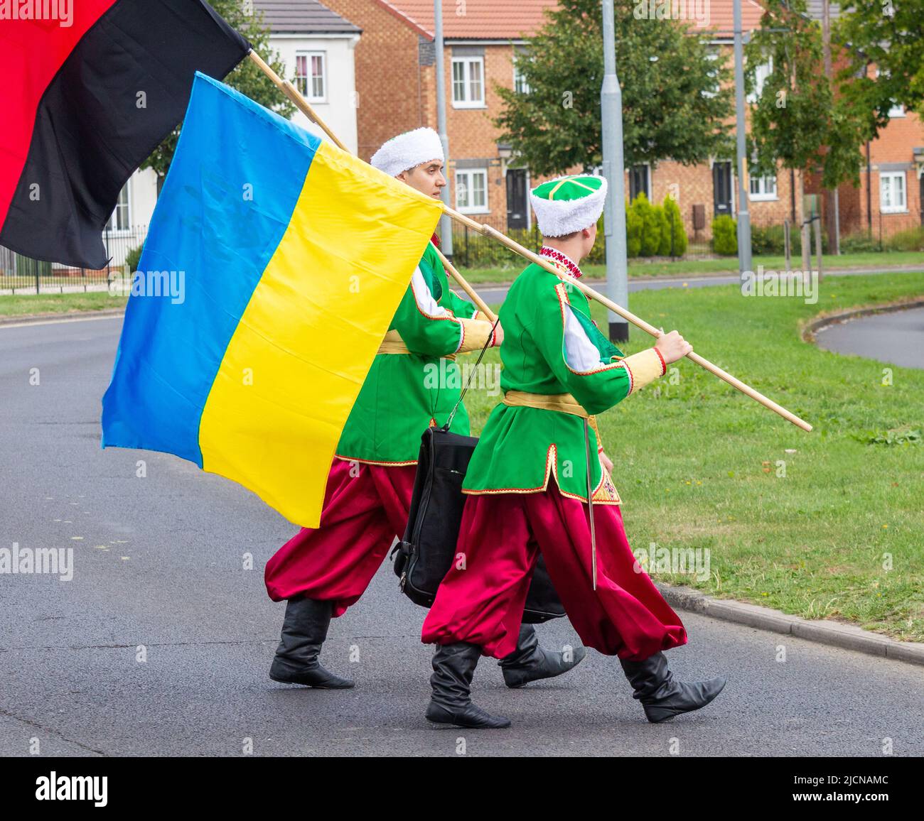 Männer aus der ukrainischen Tanzgruppe in traditioneller Kleidung. Eine Flagge der Ukraine und eine Flagge der ukrainischen Aufständischen Armee (schwarz und rot). Stockfoto
