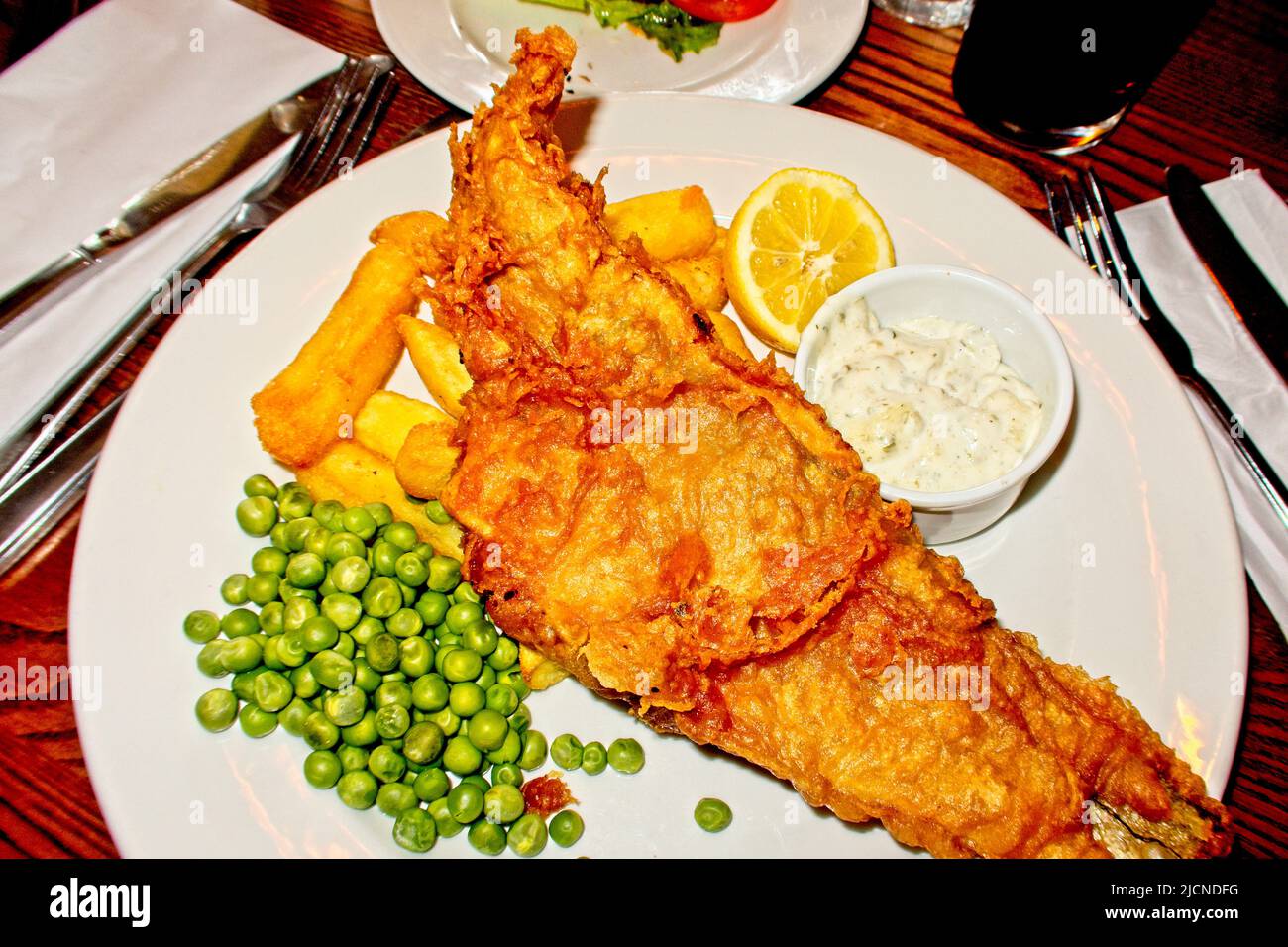 Fisch und Chips mit Erbsen und Tartarsauce serviert Stockfoto