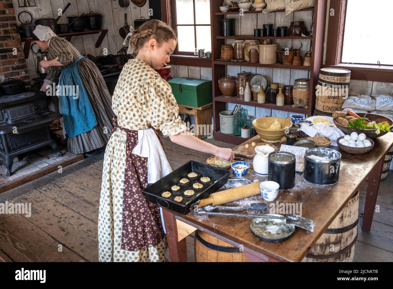 Ein Mädchen und eine Frau, die in der Küche im historischen Fort Nisqually Living Museum in Tacoma, Washington, Kekse machen Stockfoto