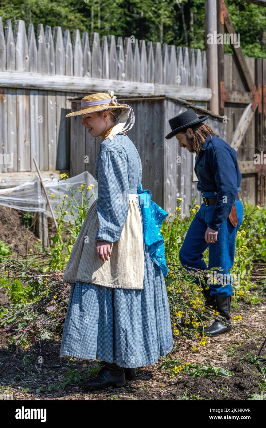 Frau und Mann, die im Garten von Fort Nisqually arbeiteten, während sie historische Kleidung aus dem Jahr 1850s trugen Stockfoto