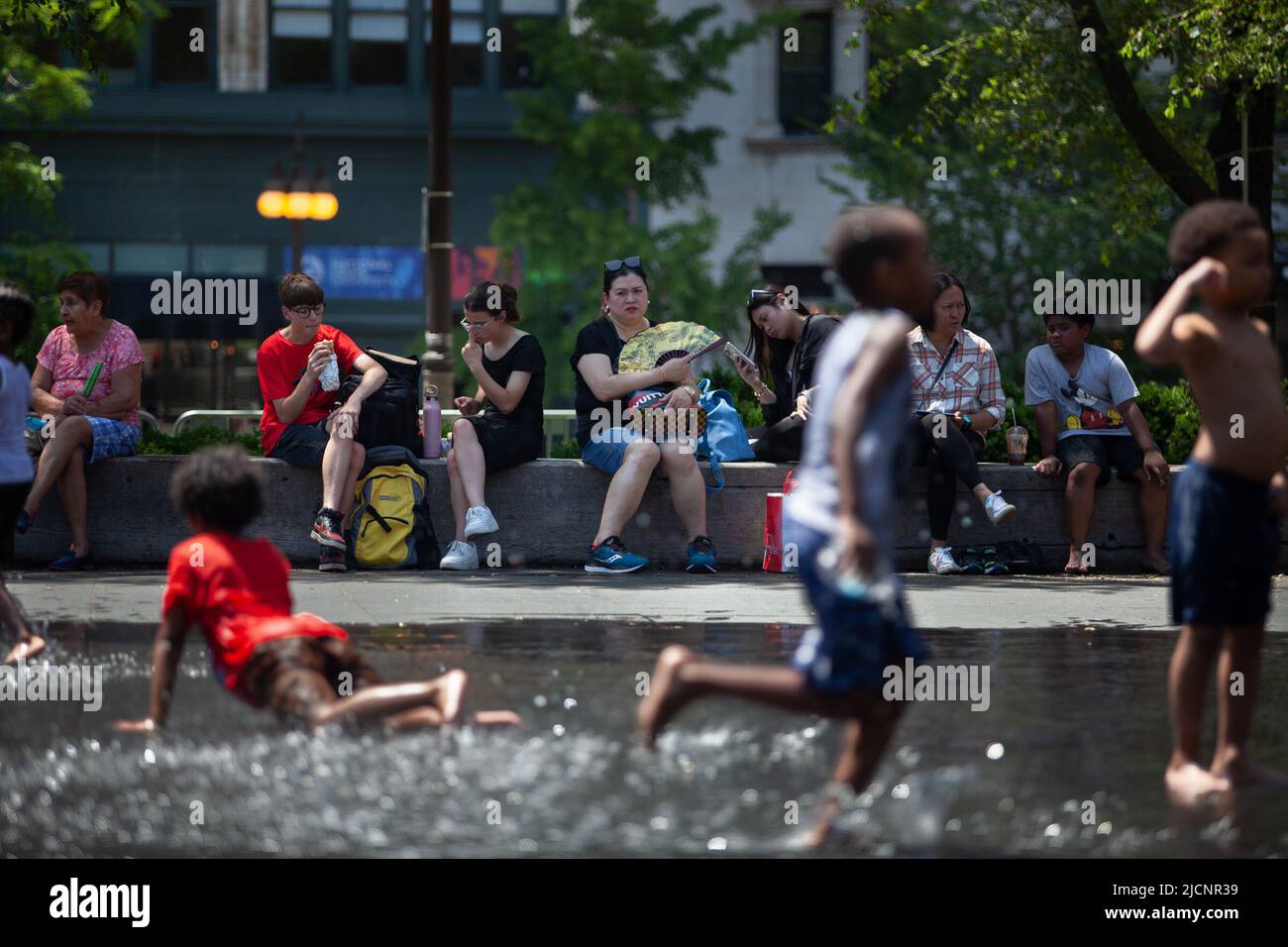 Chicago, USA. 14.. Juni 2022. Am 14. Juni 2022 sitzen Menschen im Schatten, während Kinder in der Innenstadt von Chicago, den Vereinigten Staaten, mit Wasser spielen. Die Metropolregion Chicago ist auf eine Hitzewelle in der Schwebe, da der US-Wetterdienst am Montag eine Wärmeempfehlung für die Region herausgab. Kredit: Vincent D. Johnson/Xinhua/Alamy Live Nachrichten Stockfoto