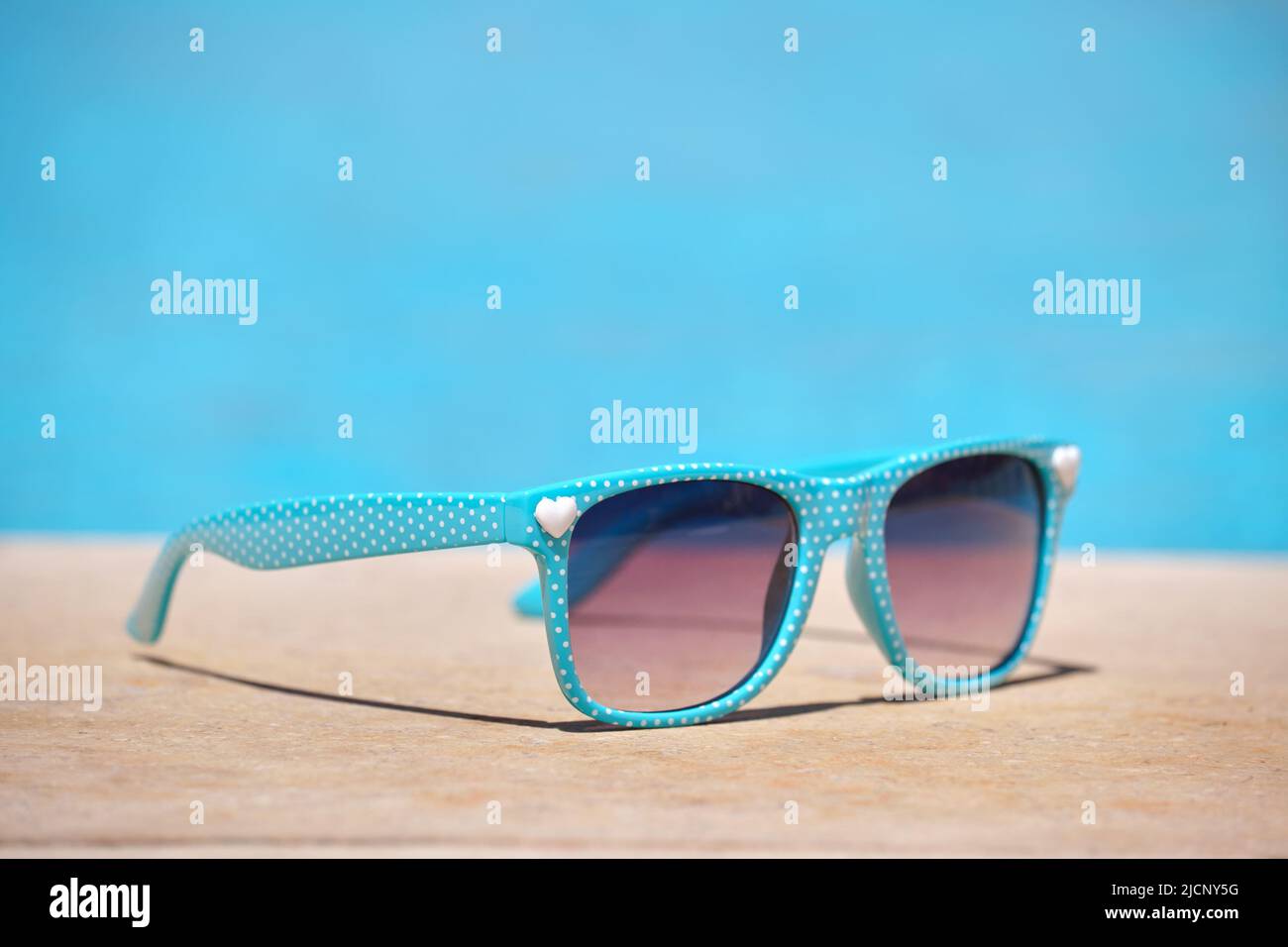 Nahaufnahme einer blauen Sonnenbrille am Pool an warmen, sonnigen Tagen. Konzept für Sommerferien Stockfoto