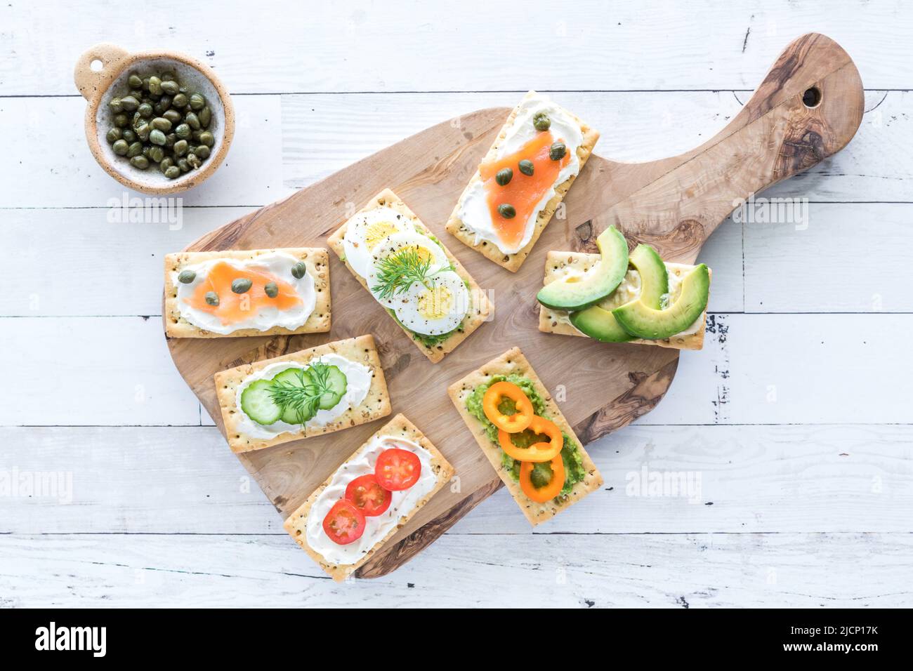 Ein Holzbrett mit allem Cracker und verschiedenen frischen Belägen. Stockfoto