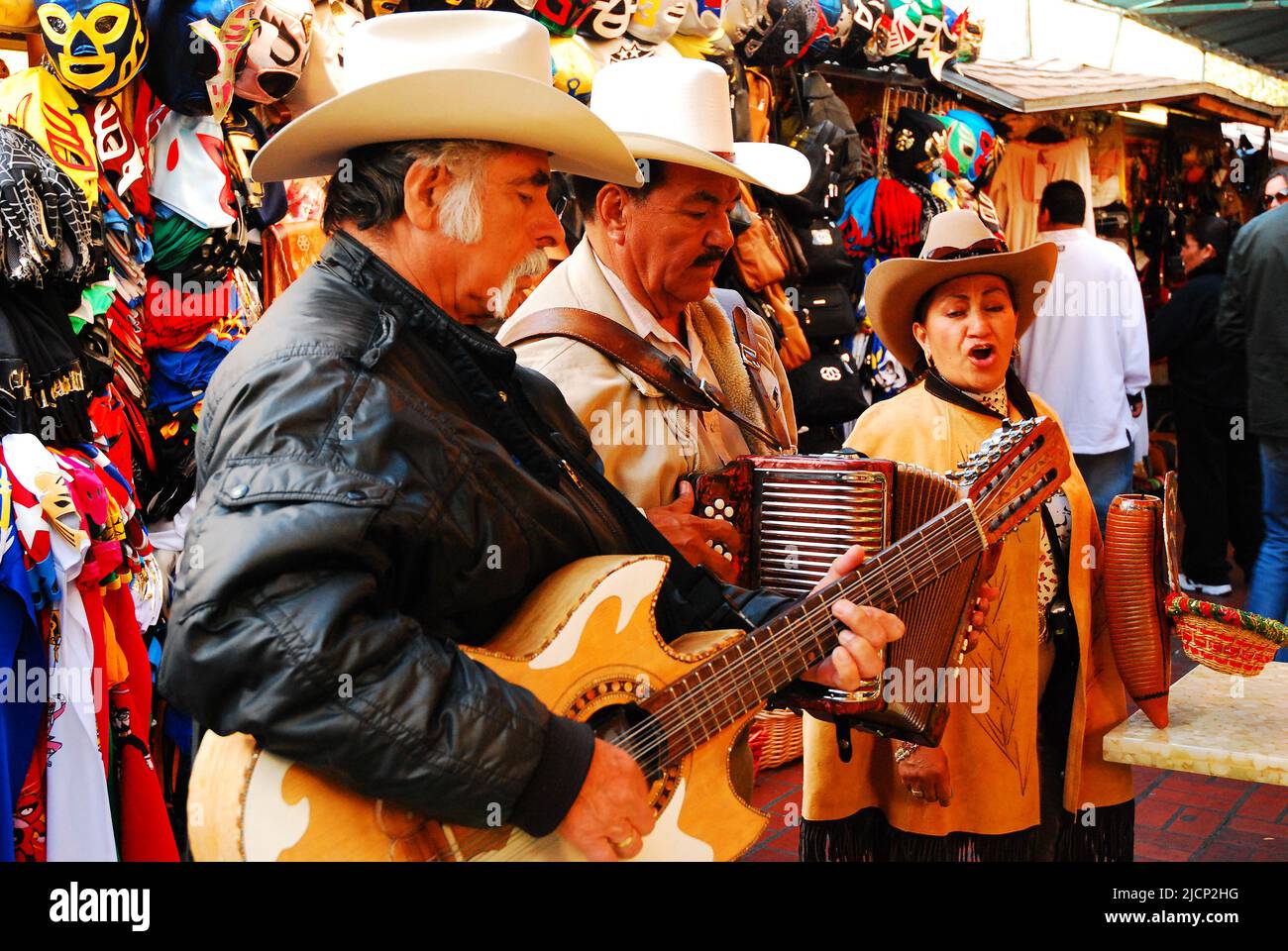 Drei Sänger und Mariachi-Musiker unterhalten ein Publikum, das traditionelle mexikanische Volkslieder in El Pueblo, einem Marktplatz in Los Angeles, singt Stockfoto