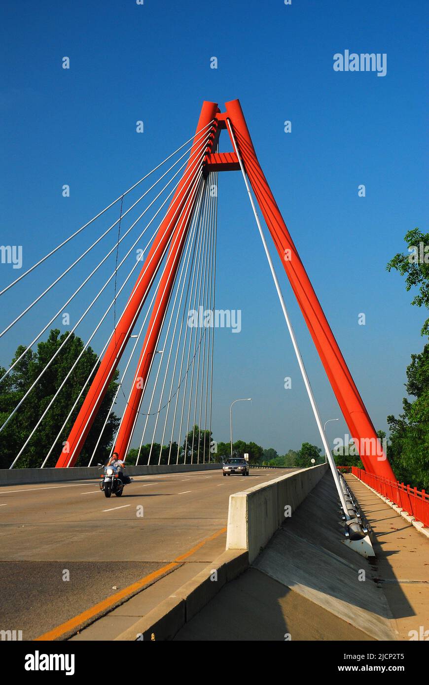 Ein Motorradfahrer fährt mit seinem Fahrrad über die Second Avenue Bridge, eine moderne rote Ingenieursstruktur in Columbus, Indiana Stockfoto