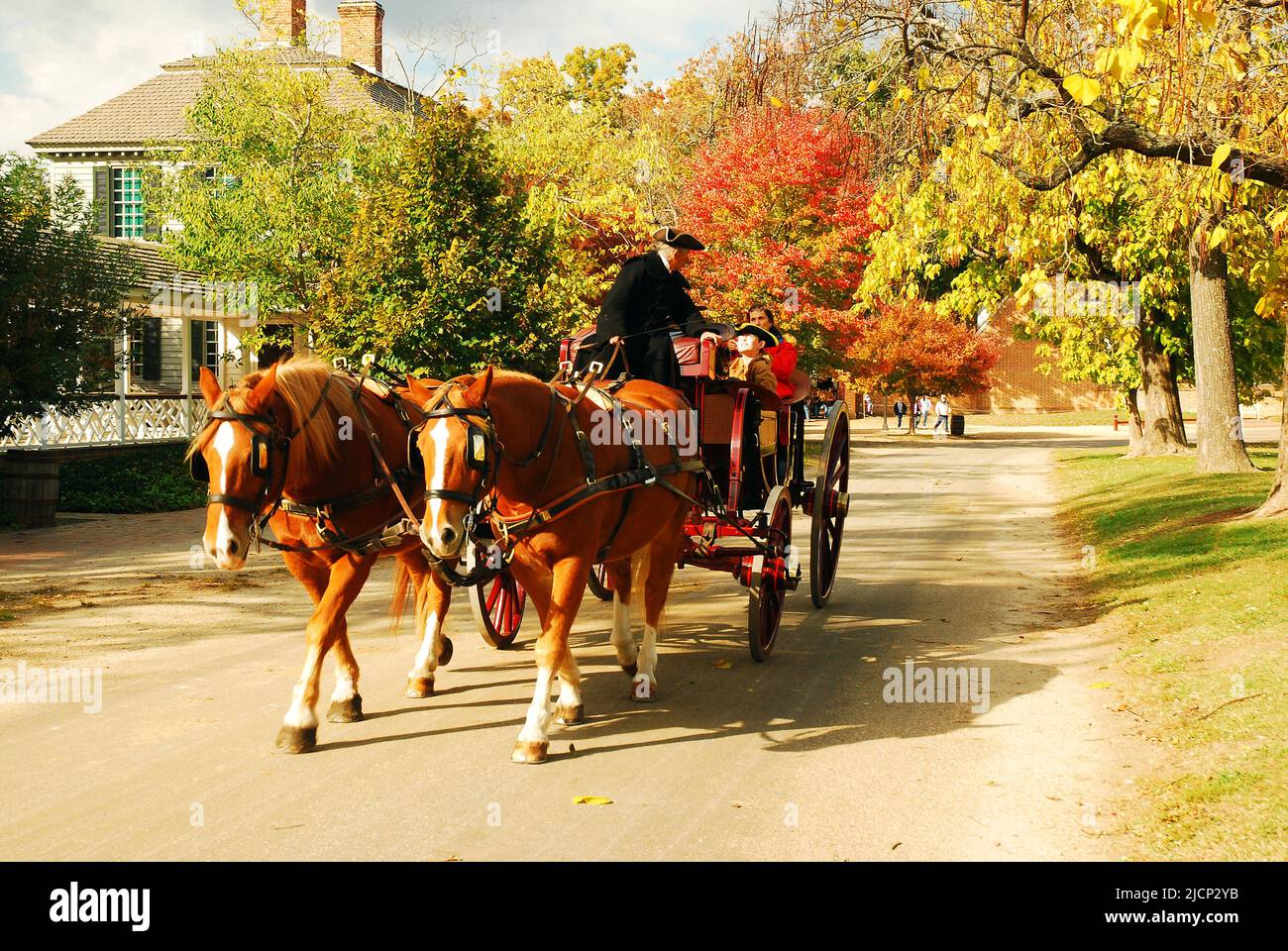 Eine Pferdekutsche führt die Besucher im Herbst auf eine entspannende Tour durch die historischen Gebäude und Häuser von Colonial Williamsburg in Virginia Stockfoto