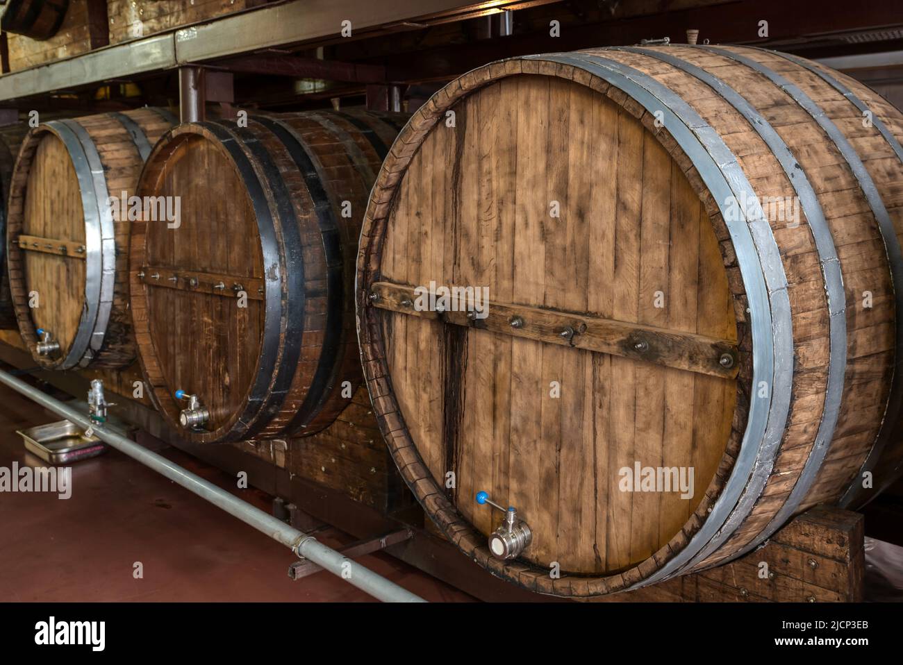 Riesige Holzfässer mit alkoholischen Getränken auf Regalen im Keller Stockfoto