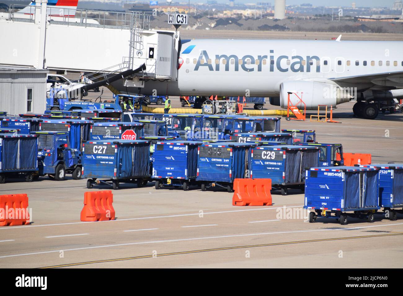 Ein Flugzeug von American Airlines, das von Mitarbeitern der Rampe bedient wird, während es am Gate C31 am Terminal C des DFW Airport (Dallas-Fort Worth Airport) geparkt ist Stockfoto
