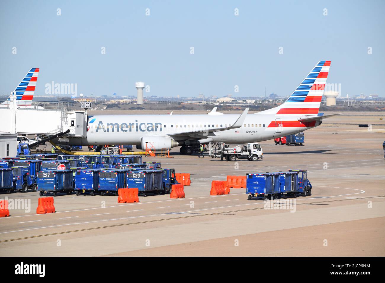 Ein Boeing 737-Flugzeug von American Airlines, das von Rampenservicemitarbeitern am Flugsteig C31 am Flughafen DFW (Dallas-Fort Worth Airport) in Terminal C gewartet wird Stockfoto