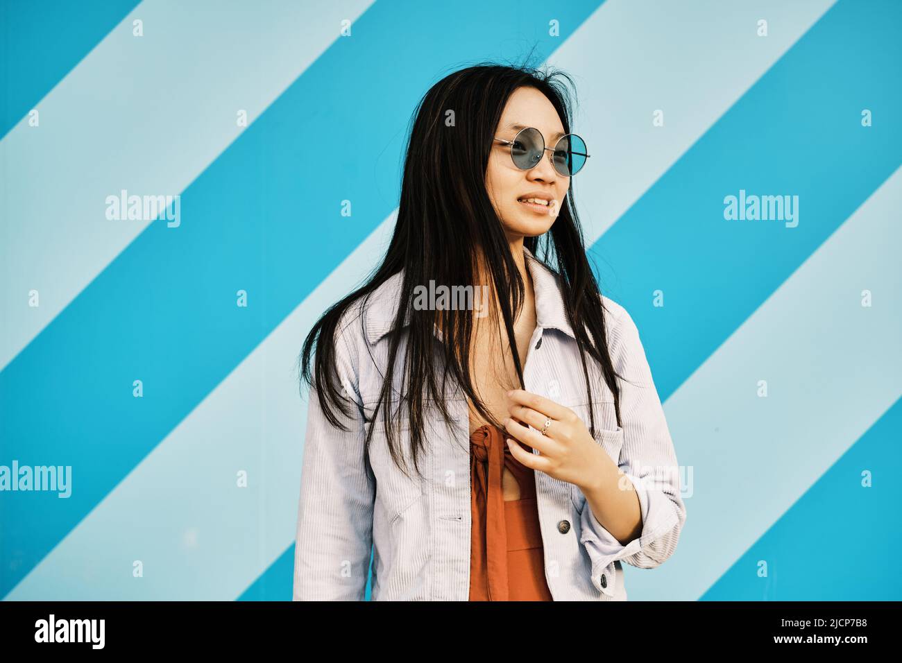 Eine junge Frau mit Sonnenbrille blickt weg und hat einen besorgten Gesichtsausdruck. Stockfoto
