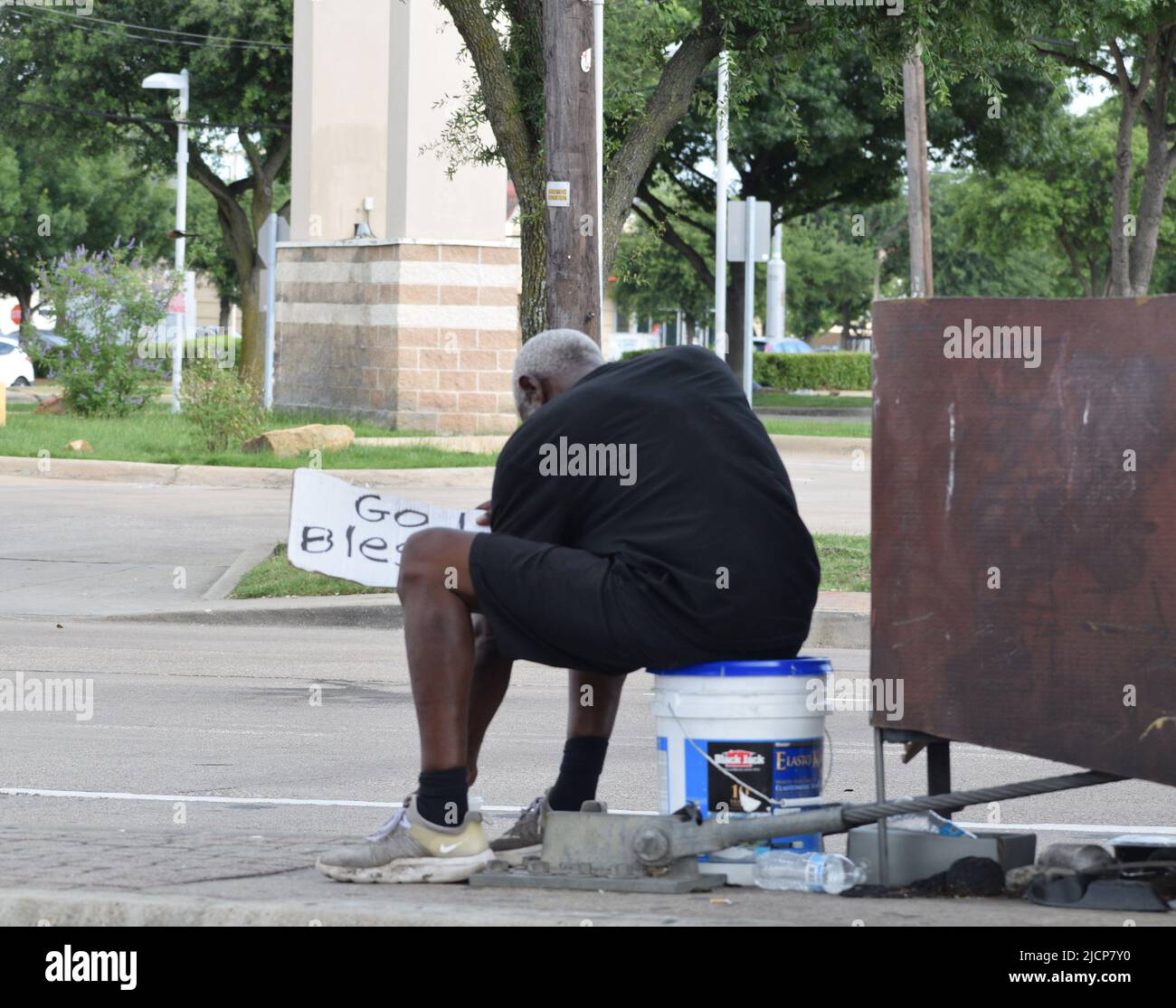 Ein obdachloser Mann in Dallas, Texas, der sich hinsetzte, ein Gottesgebet hielt und auf ein rotes Licht wartete und Autos stoppte Stockfoto