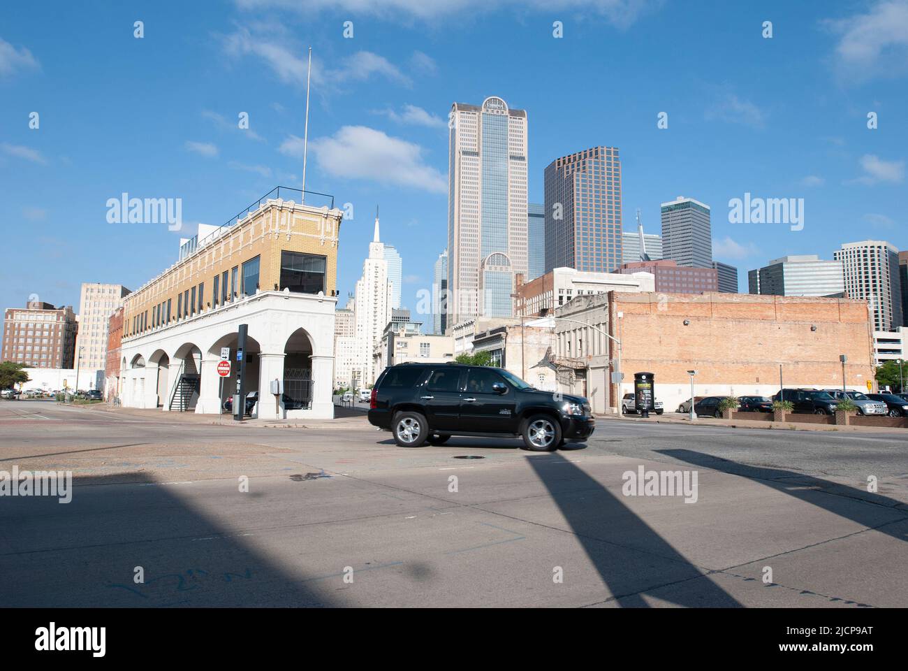 Schwarzer SUV, der nach links mit der Innenstadt von Dallas Texas im Hintergrund abbiegt, Blick nach Westen von der östlichen Seite der Innenstadt von Ca. 2013 Stockfoto