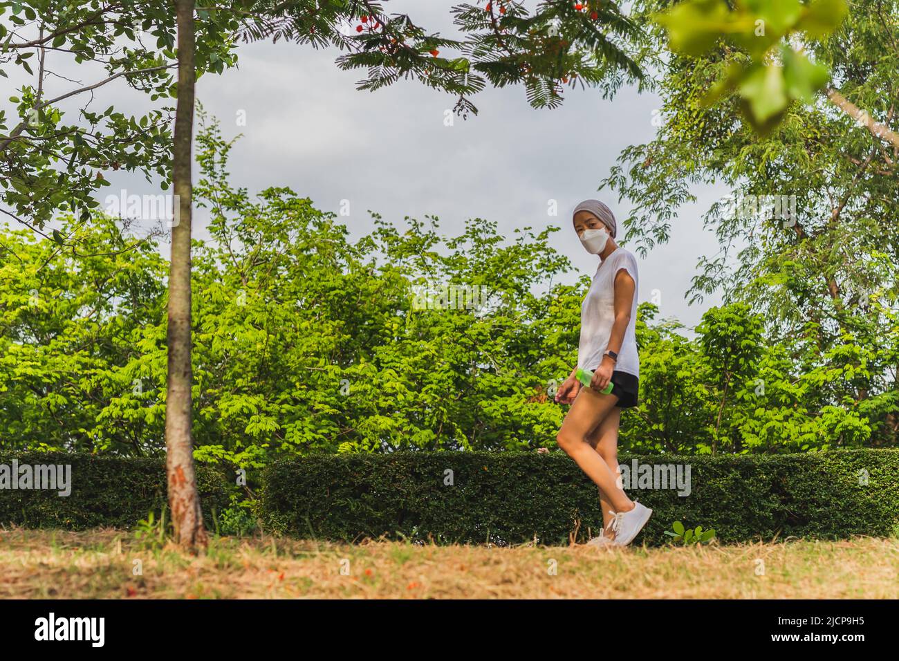 Frau in Gesichtsmaske Bewegung zu Fuß im Park. Stockfoto