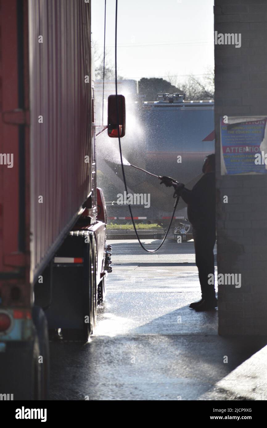 LKW-Fahrer wäscht seinen LKW an einer münzbetriebenen LKW-Waschanlage Stockfoto