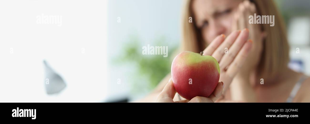 Blonde Frau weigert sich, Apfel zu essen, weil die Zähne Schmerzen Stockfoto