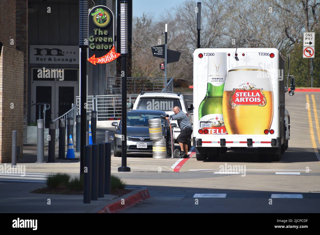 Ein Mann, der Bierkegs von seinem doppelt geparkten Bier-Lieferwagen Stella Artois an einem der Musikorte in der Toyota Music Factory in Irvin ablieferte Stockfoto