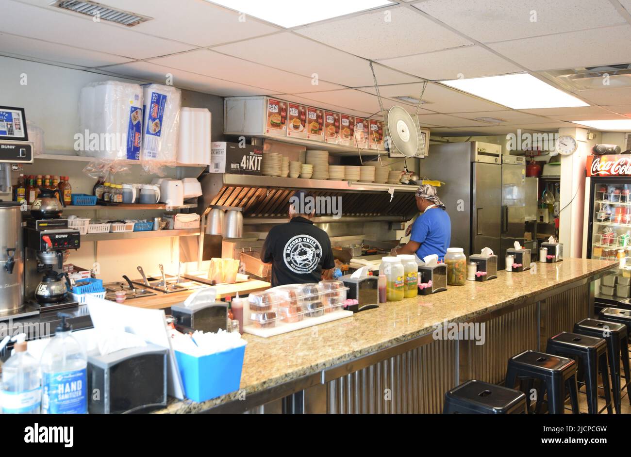 Das Innere des Record Grill, einem kleinen Loch im Wandrestaurant, in der Innenstadt von Dallas, Texas, wo ein Koch und ein Mitarbeiter hart an der Arbeit sind, um Bestellungen abzuholen Stockfoto
