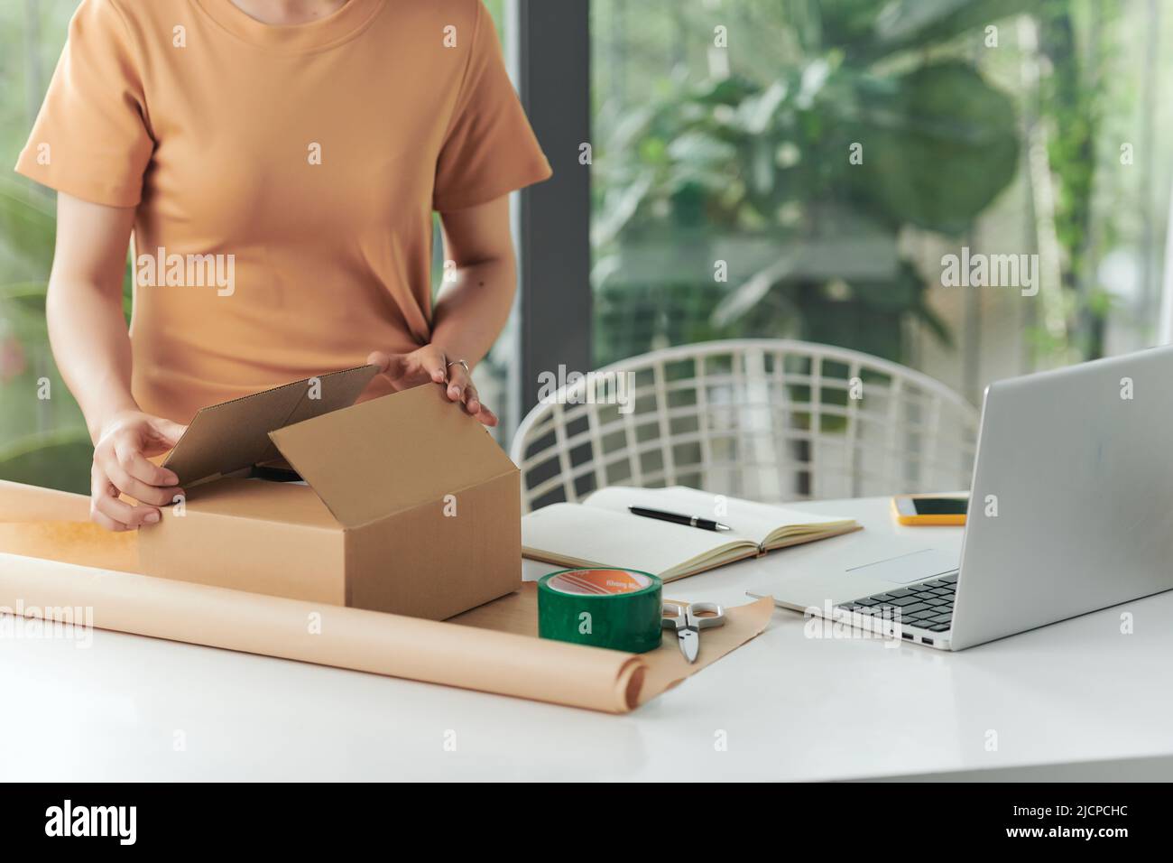 Privates Geschäftskonzept. Eine Frau, die mit einem Verpackungskarton für die Lieferung im Home-Office arbeitet. Stockfoto