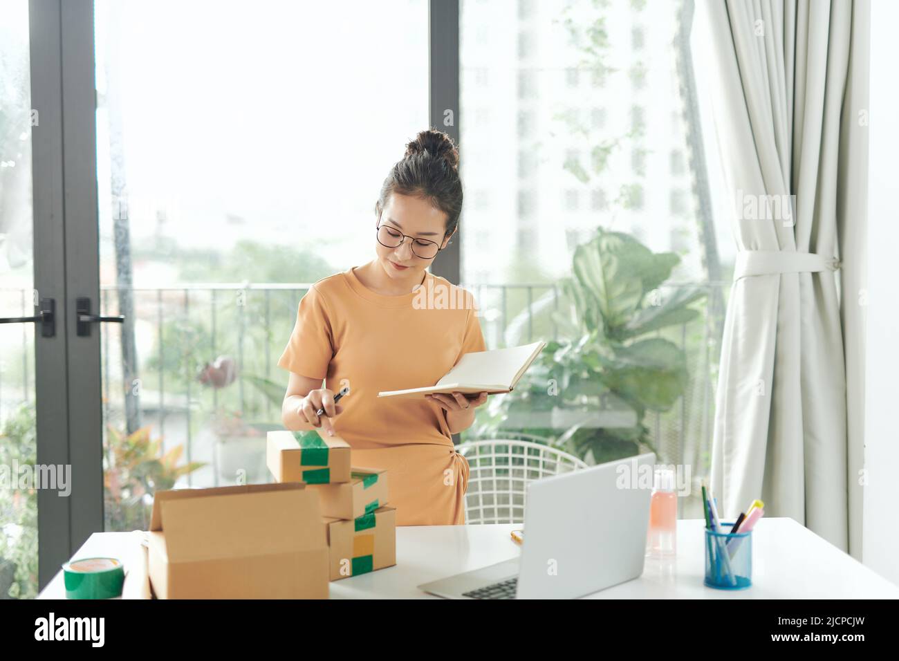 Privates Geschäftskonzept. Eine Frau, die mit einem Verpackungskarton für die Lieferung im Home-Office arbeitet. Stockfoto