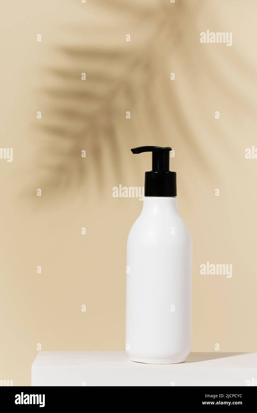 Leere, nachfüllbare Spenderflasche auf gelbem Hintergrund mit Palmblatt-Schatten Stockfoto