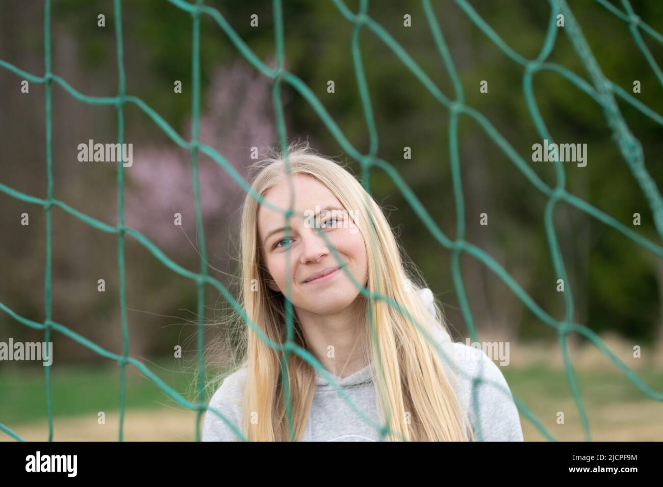 Porträt einer jungen blonden Frau durch ein Fußball- oder Fußballnetz Stockfoto