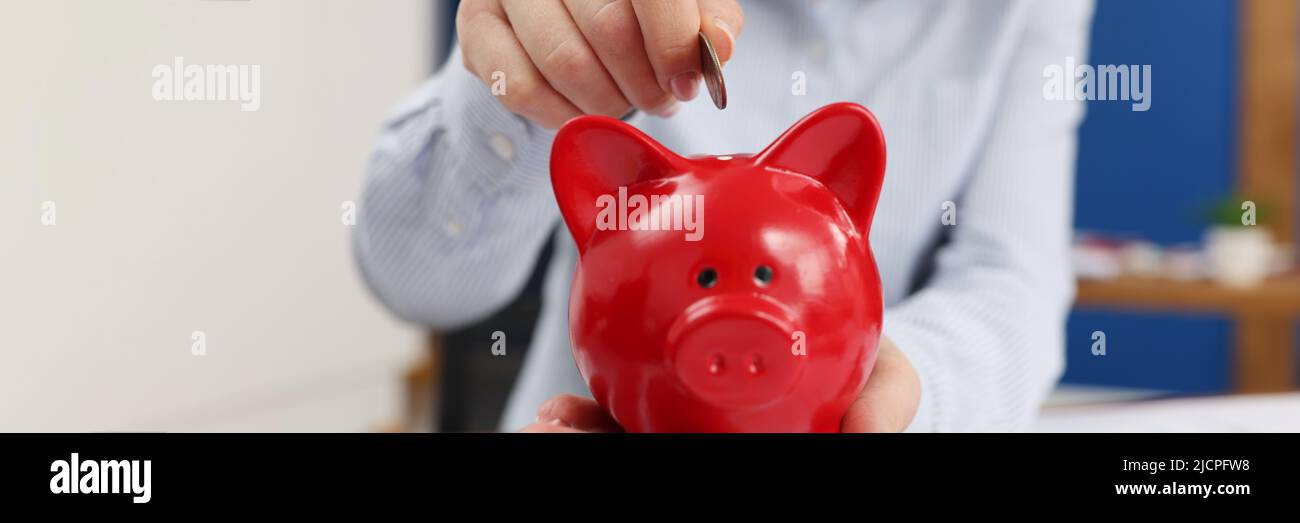 Geschäftsfrau wirft Münzen in Sparschwein am Tisch mit Grafiken aus der Nähe Stockfoto