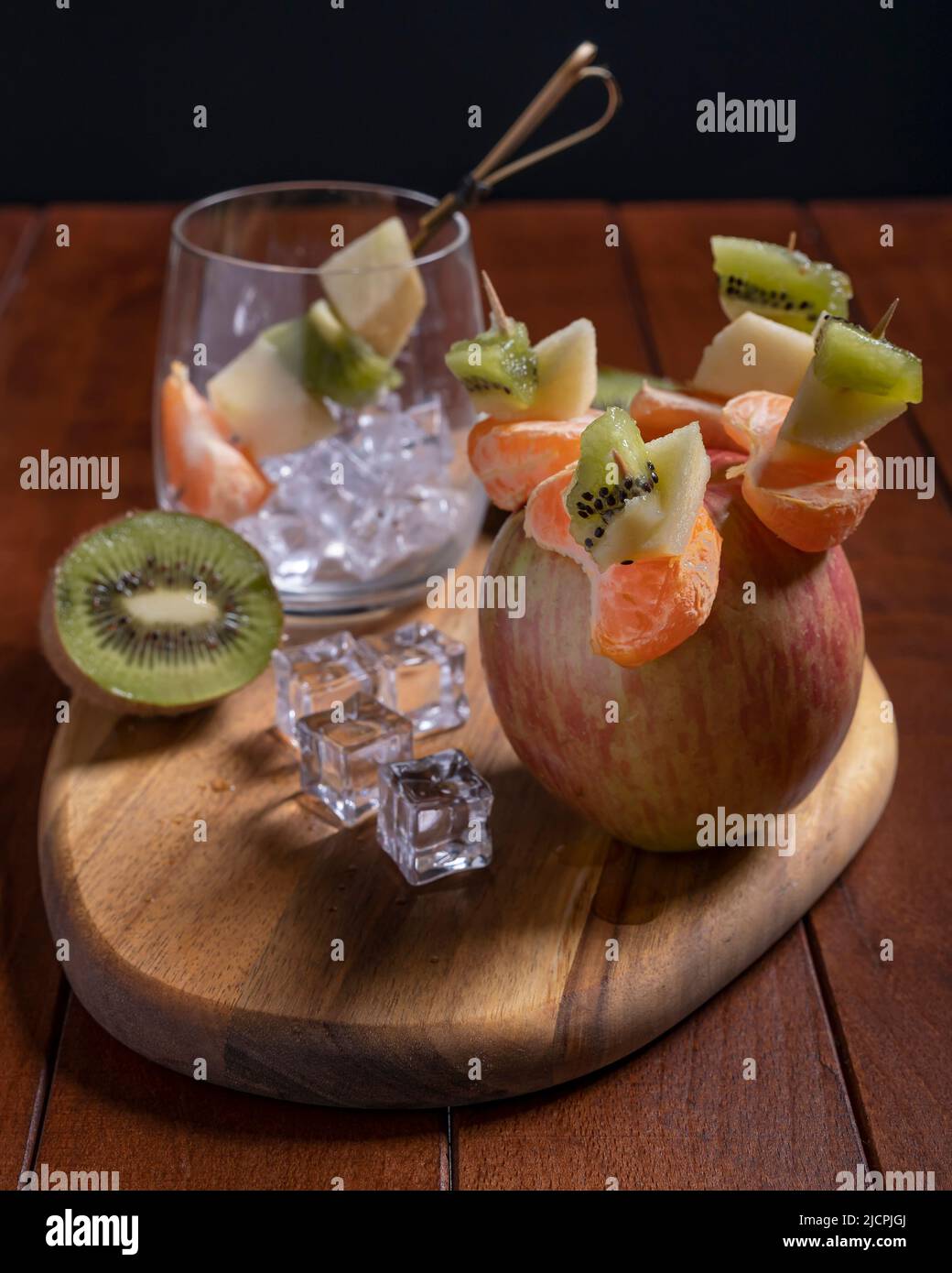 Leckere Obstspieße mit Apfel, Mandarine und Kiwi auf Holztisch Stockfoto