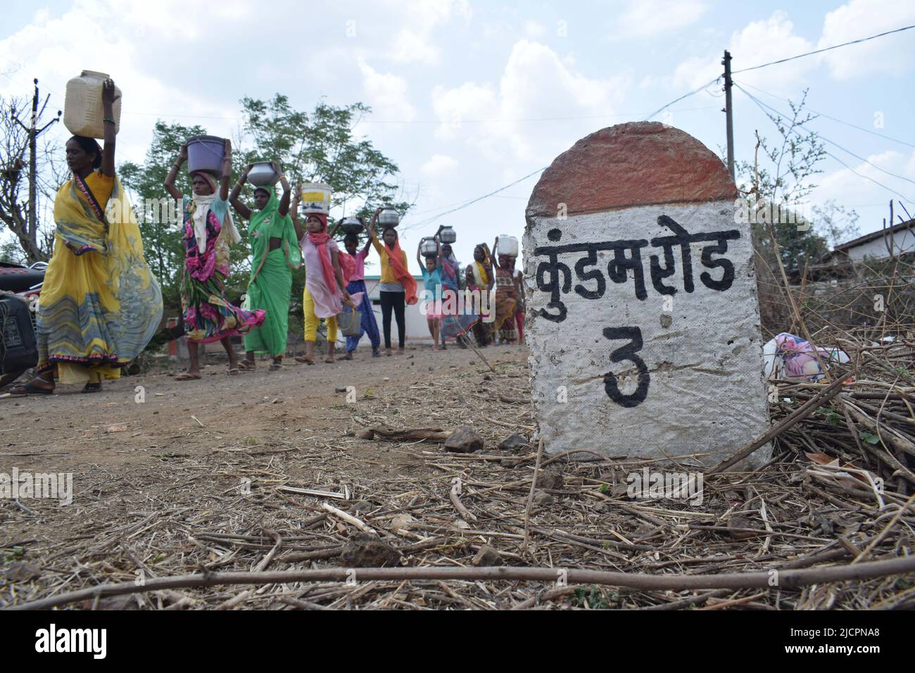 Die Inder einer Aboriginal 'Kol' Gemeinde füllen Trinkwasser in Stahl- und Kunststoffbehältern aus einem Brunnen im Dorf Nawargawa, Madhya Prades Stockfoto