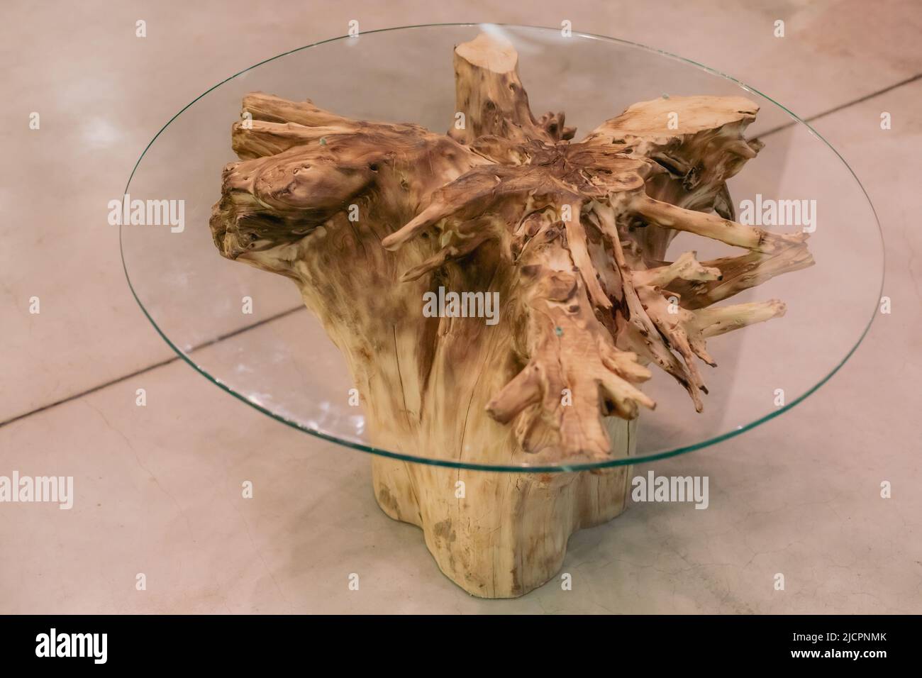 Handgefertigter Holztisch aus der trockenen Wurzel des Baumes und runde Glastafel. Baumwurzelmöbel Stockfoto