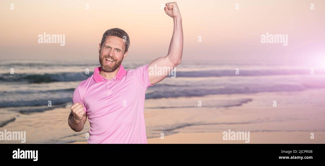 Mann Gesicht Porträt, Banner mit Kopierraum. Erfolgreicher Kerl am Sonnenaufgangsstrand. Bärtiger Mann im Hemd. Feiern Sie Erfolg. Sommerurlaub. Stockfoto