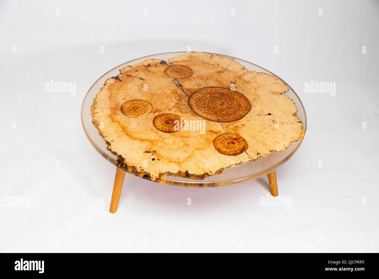Runder Holztisch aus Epoxidharz, verziert mit Fladenbroten auf weißem Hintergrund. Kreatives Tischdesign Stockfoto